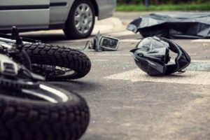 A crashed motorcycle and discarded helmet lie on the pavement.